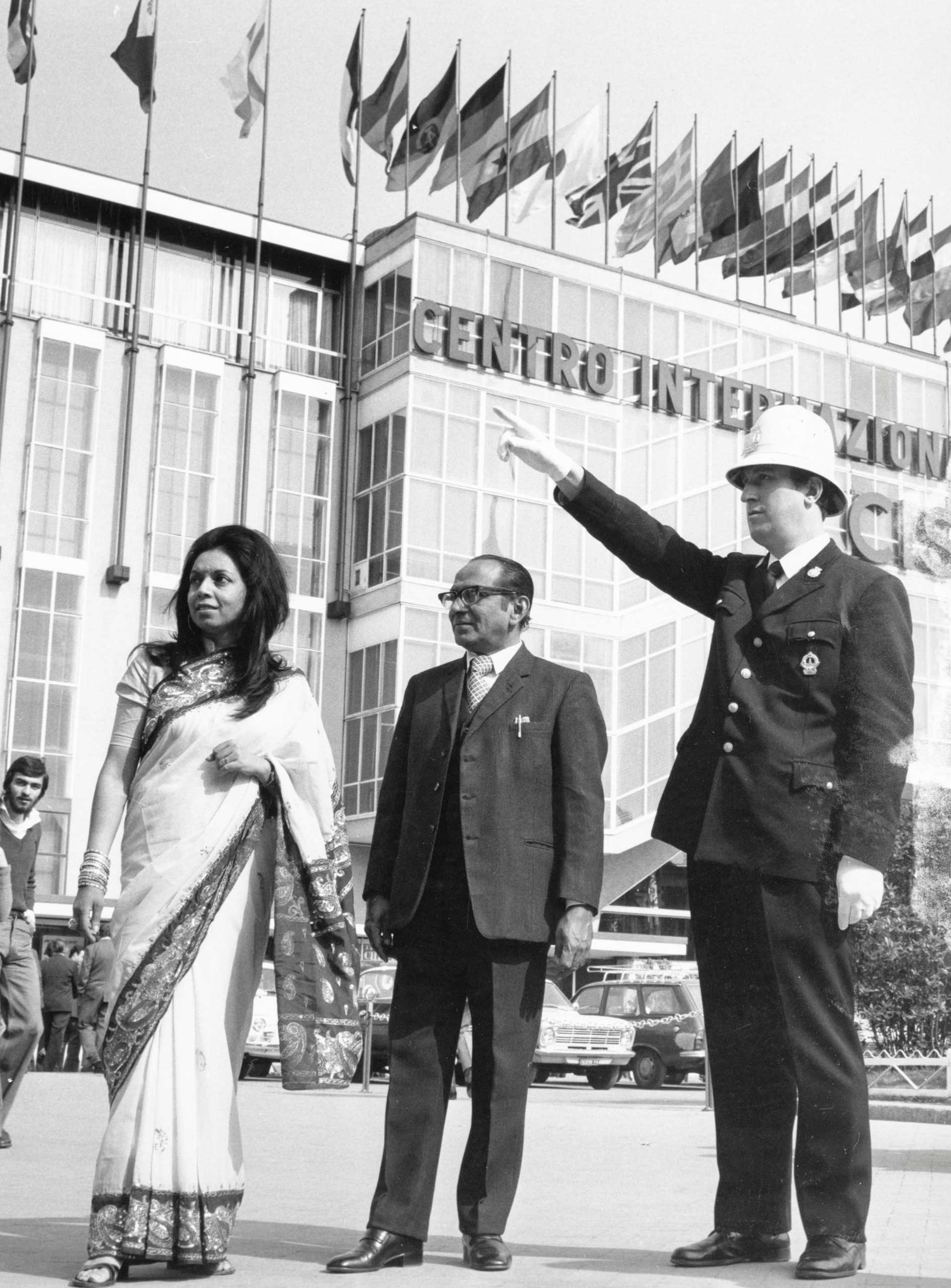 Publifoto, vigile urbano con visitatori stranieri alla Fiera Campionaria di Milano del 1975. © Fondazione Fiera Milano/Publifoto.