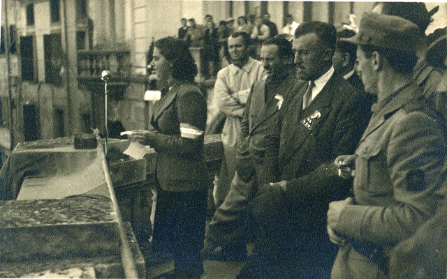 Autore non identificato, comizio da palazzo D'Aronco; si riconosce, secondo da destra, il comandante Emilio Grossi “Vincenzi” delle formazioni unificate Garibaldi-Osoppo. Udine, 2 maggio 1945. © ANPI Comitato Provinciale di Udine.